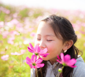 girl smelling a flower in a field