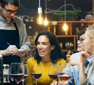 woman smiling surrounded by friends ordering at a restaurant