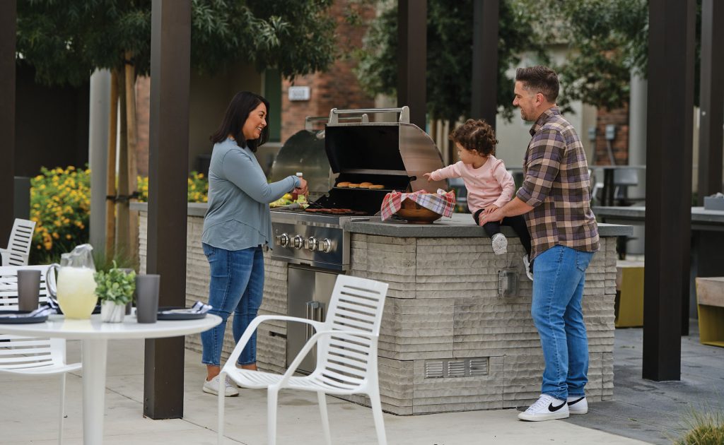 Parents with toddler-aged child grilling hamburgers