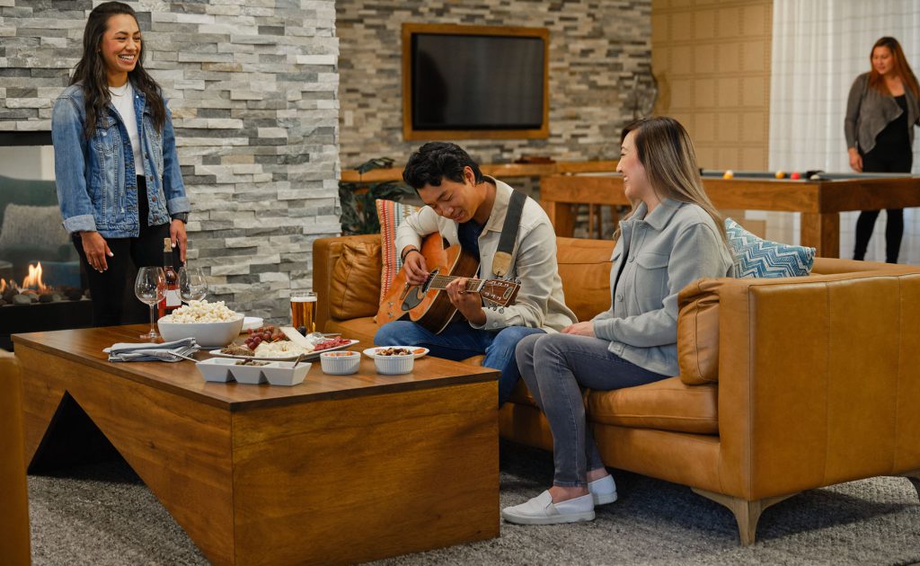 young man playing guitar with friends gather around