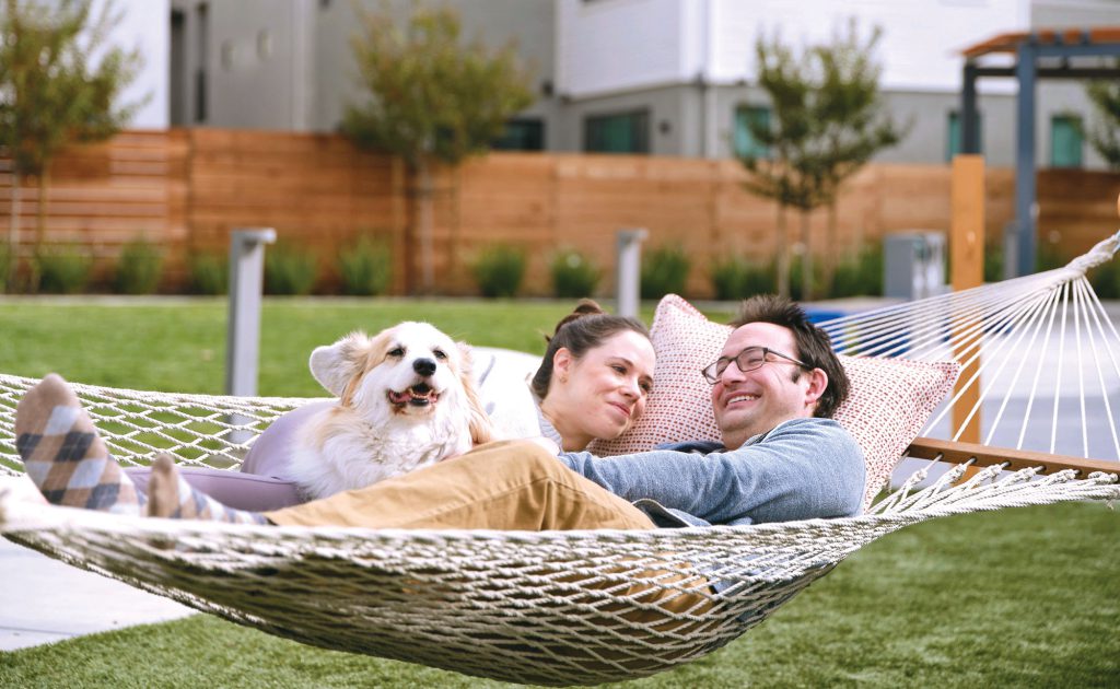 couple relaxing in a hammock with their dog at the rec center